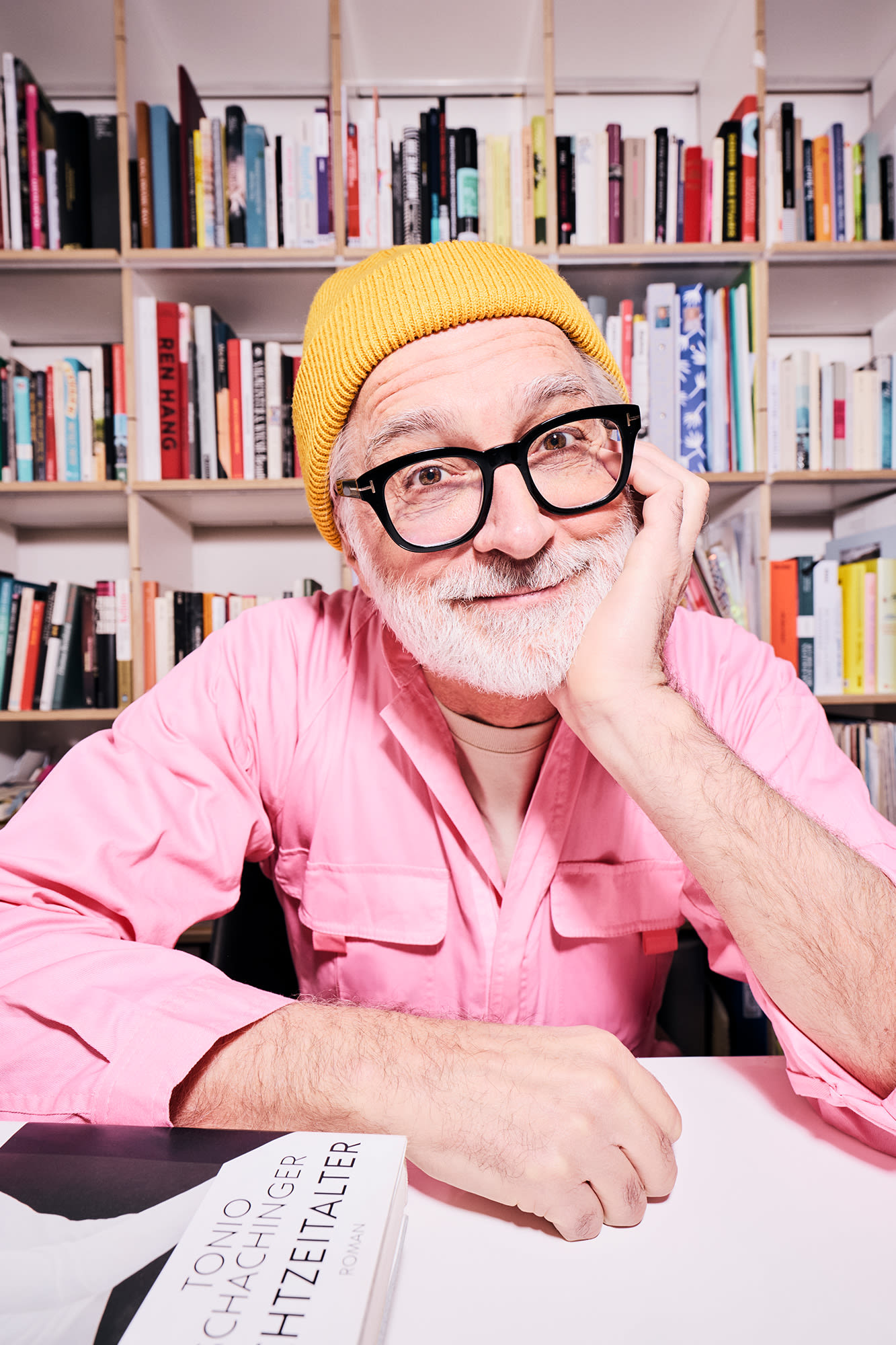 Mann mit rosa Hemd vor Bücherregal – klassische Anlageformen für generationenübergreifendes Vermögen