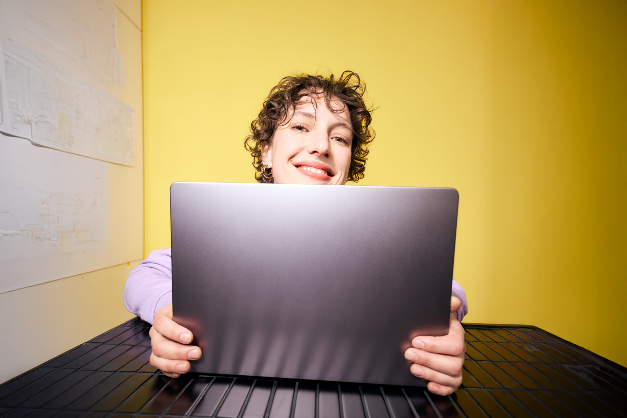 Junge Frau arbeitet am Laptop vor gelbem Hintergrund – flexibel investieren mit Fondssparen bei der BKS Bank.