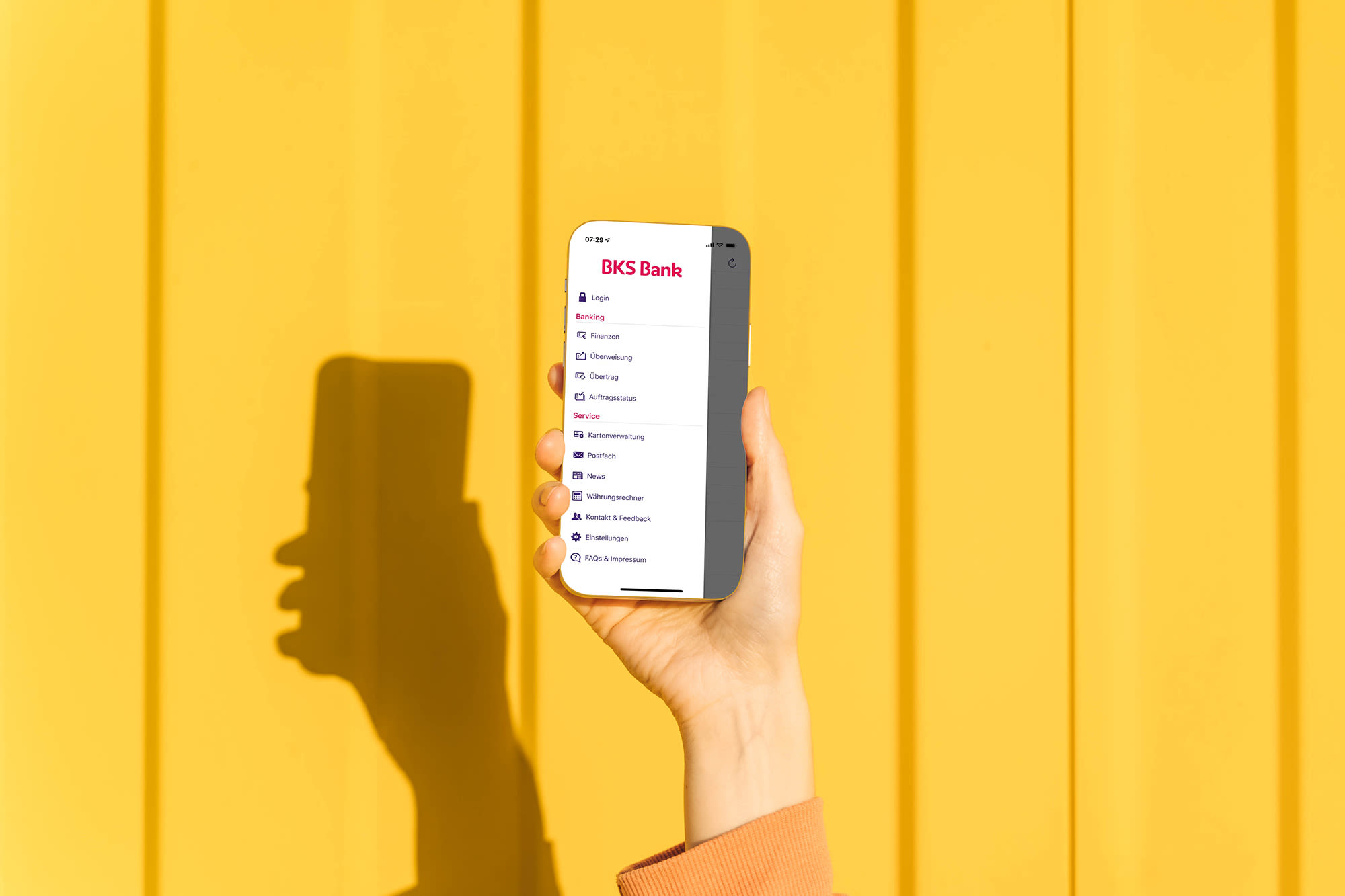 Hand mit Smartphone vor gelbem Hintergrund Hand mit Smartphone vor gelbem Hintergrund