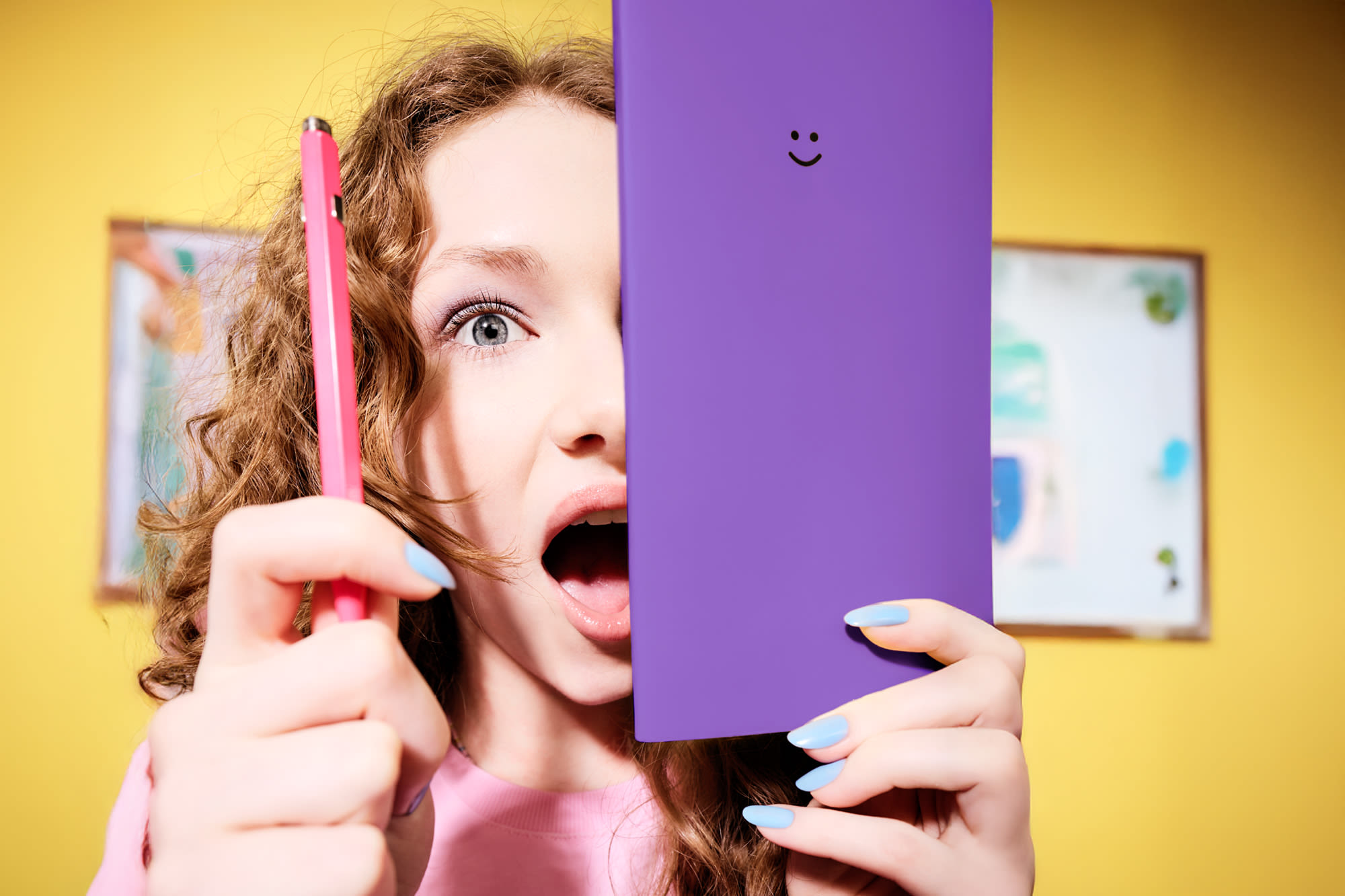 Junge Frau mit roten Locken hält lila Buch mit Smiley. Junge Frau mit roten Locken hält lila Buch mit Smiley.